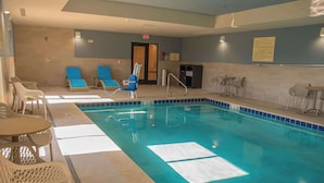 A swimming pool with lounge chairs and tables, a poolside area, and a door leading to an exit. - Hampton Inn Wabash (Wabash)