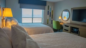 A hotel room with two beds, a desk, a chair, a television, and a window with a view of the beach. - Hampton Inn Wabash (Wabash)