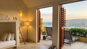Ein Hotelzimmer mit Bett, einer Sitzecke, einer Stehlampe und Blick ins Freie.