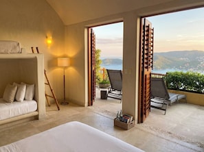 A hotel room with a bed, a sofa, a standing lamp, and a view of the outdoors. - Luxury Home with Breathtaking Views in Zihuatanejo (Zihuatanejo)