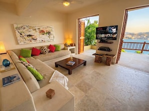 A living room with a sofa, coffee table, and a TV displaying Netflix. - Luxury Home with Breathtaking Views in Zihuatanejo (Zihuatanejo)