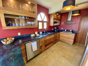 Une cuisine avec des meubles de rangement en bois, un plan de travail noir et un lave-vaisselle en acier inoxydable.
