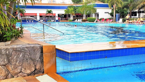 A swimming pool with a stone and blue tiled edge, surrounded by lounge chairs and a restaurant named "Peter & Peter Restaurant" in the background. - View Talay 2A, 5th Floor Studio Condo (Pattaya)