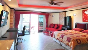 A hotel room with a bed, a desk, a chair, a TV, and a ceiling fan. - View Talay 2A, 5th Floor Studio Condo (Pattaya)