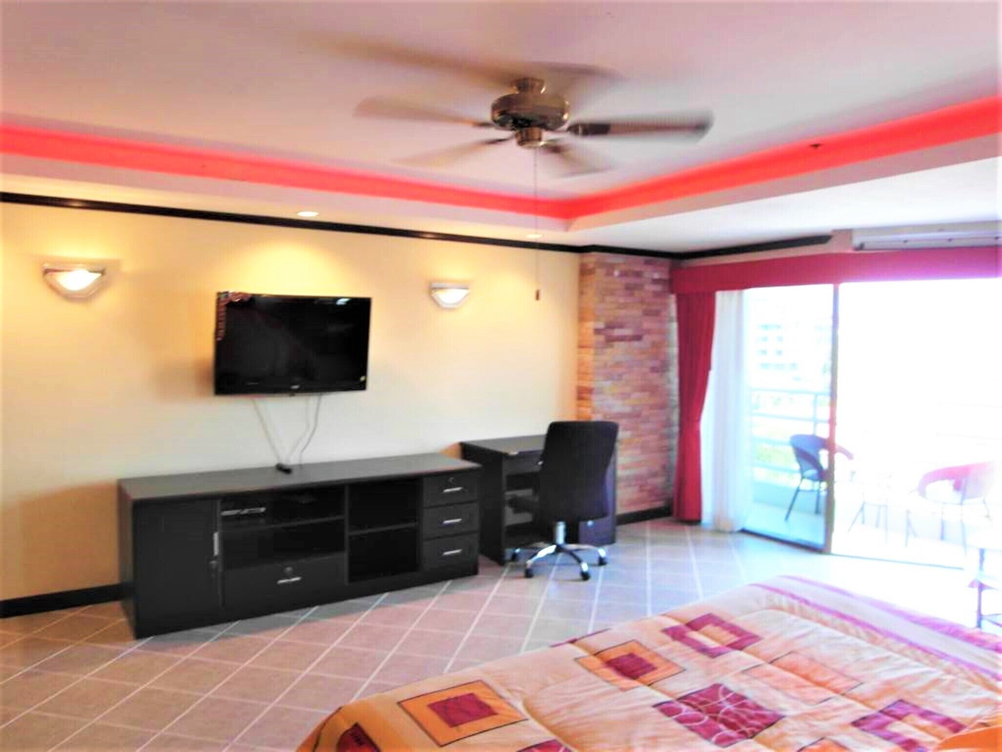 Une chambre d’hôtel avec un lit, un bureau, une télévision et un balcon équipé de chaises.