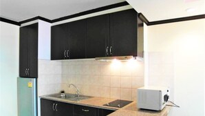 A kitchen with dark cabinets, a stainless steel refrigerator, a double sink, and a microwave. - View Talay 2A, 5th Floor Studio Condo (Pattaya)