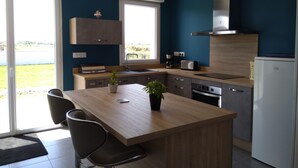 Een moderne keuken met een centraal eiland, inbouwapparatuur en grote ramen met uitzicht op de omgeving.