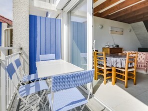 Cozy attic room with a sloped ceiling, featuring a dining table, blue chairs, and a small cabinet.