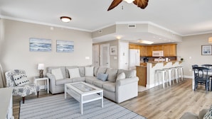 Ein geräumiges Wohnzimmer mit Ecksofa, Couchtisch und Deckenventilator.