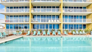 Ein Hotel mit Poolbereich, mehreren Balkonen und Sitzgelegenheiten im Freien.