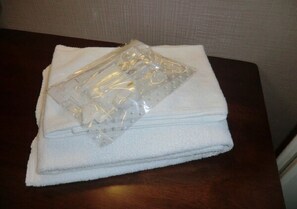 A folded white towel and a clear plastic bag on a dark wooden table.