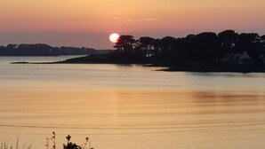A sunset over a calm lake with a distant shoreline and trees. - Grande Maison Avec vue Imprenable sur L'aber-wrac'h (Plouguerneau)