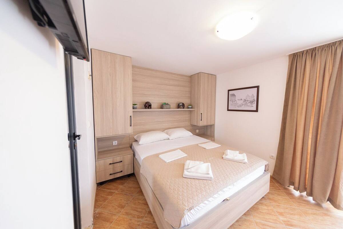 Un dormitorio ordenado con cama, armario y mesita de noche.