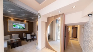 A modern living room with a flat-screen TV, a sofa, and a coffee table. - Azzuro Apartments (Budva)