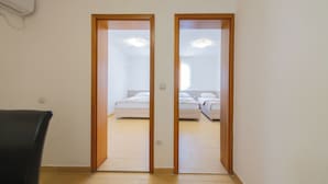 A room with a bed, a chair, and a door leading to another room. - Azzuro Apartments (Budva)