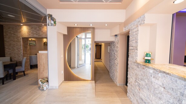 A modern hotel lobby with a reception desk, a curved mirror, and a dining area with a wooden floor. - Azzuro Apartments (Budva)