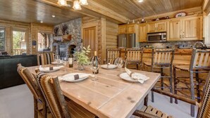 A wooden interior with a dining table set for four, kitchen appliances, and a stone fireplace. - Abode at Black Bear #253, hot tub, pool & gym, Deer Valley (Park City)