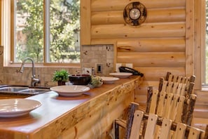 A wooden interior with a kitchen counter, a sink, and a dining area with chairs.