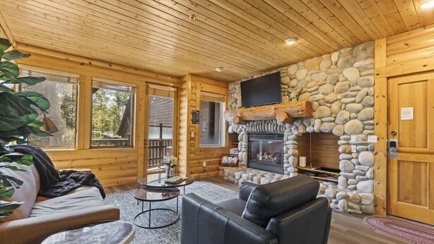 A log cabin interior with a stone fireplace, leather furniture, and large windows. - Abode at Black Bear #353, private hot tub, pool, Deer Valley (Park City)