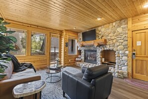A log cabin interior with a stone fireplace, leather furniture, and large windows. - Abode at Black Bear #353, private hot tub, pool, Deer Valley (Park City)