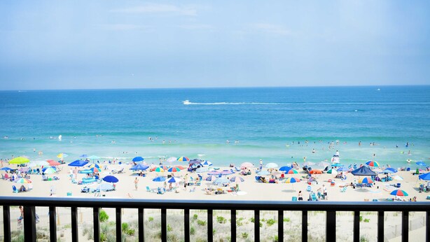 A beach with numerous umbrellas and people. - Relax in this 2 BD/2Bath Direct Ocean Front. Listen to the ocean waves and enjoy. (OCEAN CITY)