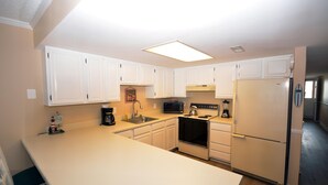 A kitchen with white cabinets, a microwave, a stove, and a refrigerator. - Relax in this 2 BD/2Bath Direct Ocean Front. Listen to the ocean waves and enjoy. (OCEAN CITY)