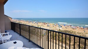 A balcony with a view of a beach with umbrellas and people. - Relax in this 2 BD/2Bath Direct Ocean Front. Listen to the ocean waves and enjoy. (OCEAN CITY)