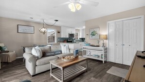 A living room with a sofa, coffee table, and a kitchen in the background. - Beachy, Modern & Updated - Seagrove Beach on 30A + Free Attraction Tickets! (Santa Rosa Beach)