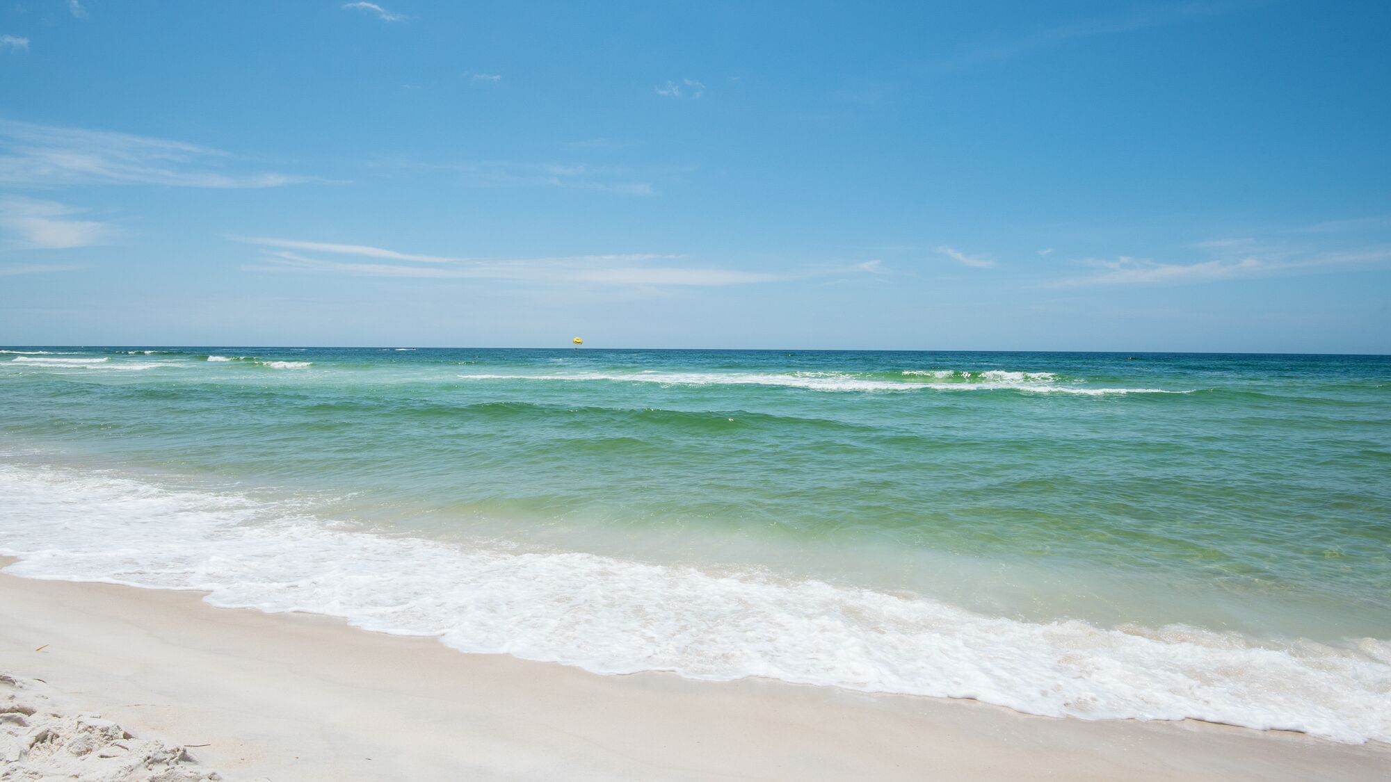 A beach with clear water and a sandy shore.