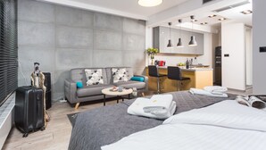 Une chambre d’hôtel moderne dotée d’un grand lit, d’un canapé, d’une petite table, d’une kitchenette et d’un coin repas.