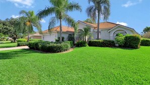 A residential house with a well-maintained lawn, palm trees, and a clear blue sky. - SUPERB LAKESIDE VILLA WITH PRIVATE HEATED POOL - NAPLES (Naples)