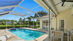 A covered outdoor swimming pool with lounge chairs and a table, surrounded by a landscaped garden and a house in the background. - SUPERB LAKESIDE VILLA WITH PRIVATE HEATED POOL - NAPLES (Naples)