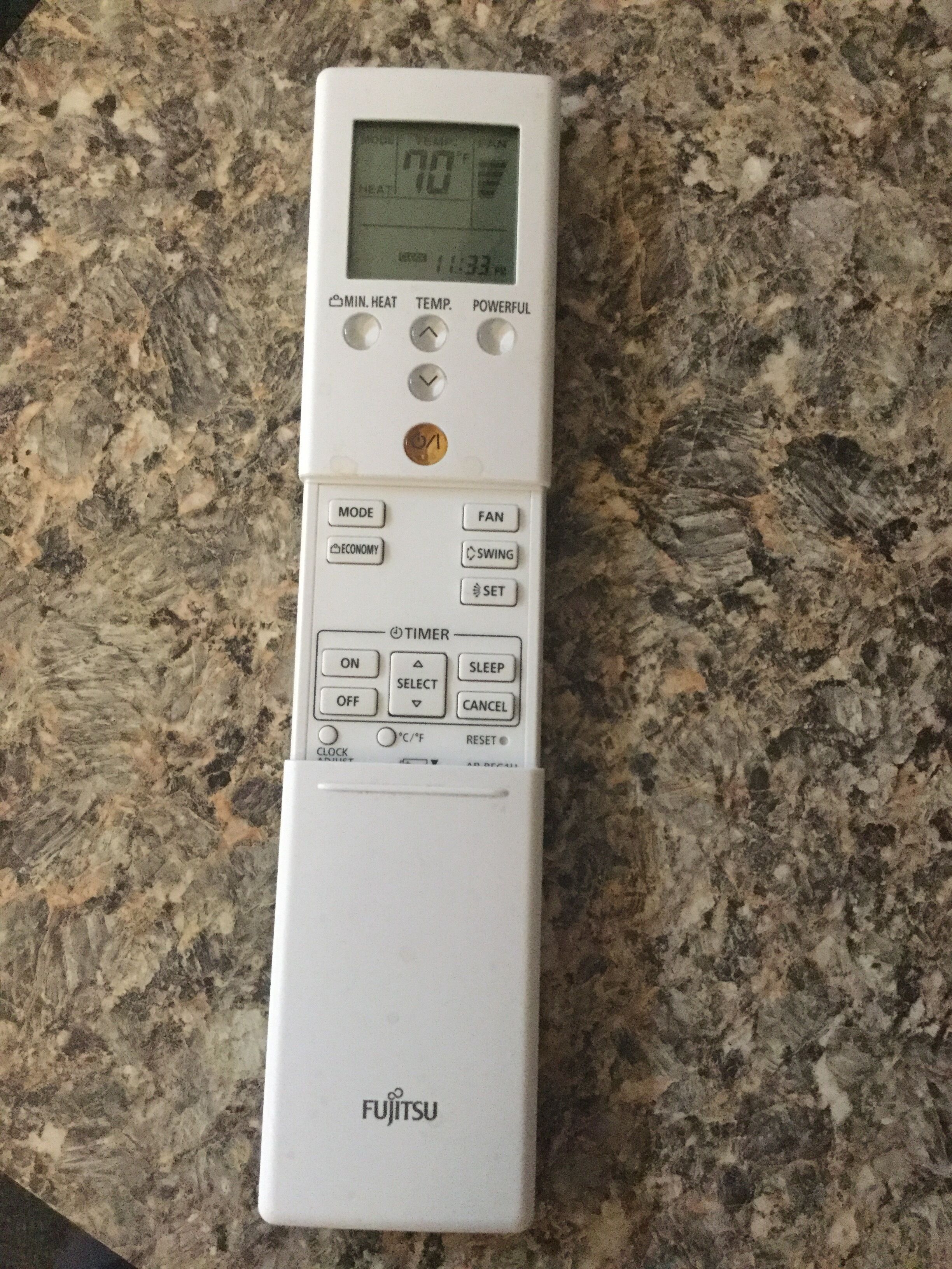A white Fujitsu thermostat on a granite countertop.