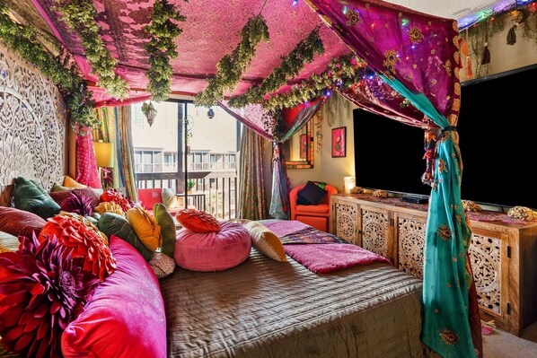 Ein Zimmer mit einem Bett, einem Fernseher und einem Balkon mit Blick.