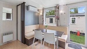 A compact, well-lit room with a kitchenette, a seating area with a table and chairs, and a large window offering a view of the backyard. - Beautiful private villa for 6 guests with pool, A/C, WIFI, terrace and pets allowed (Prague)