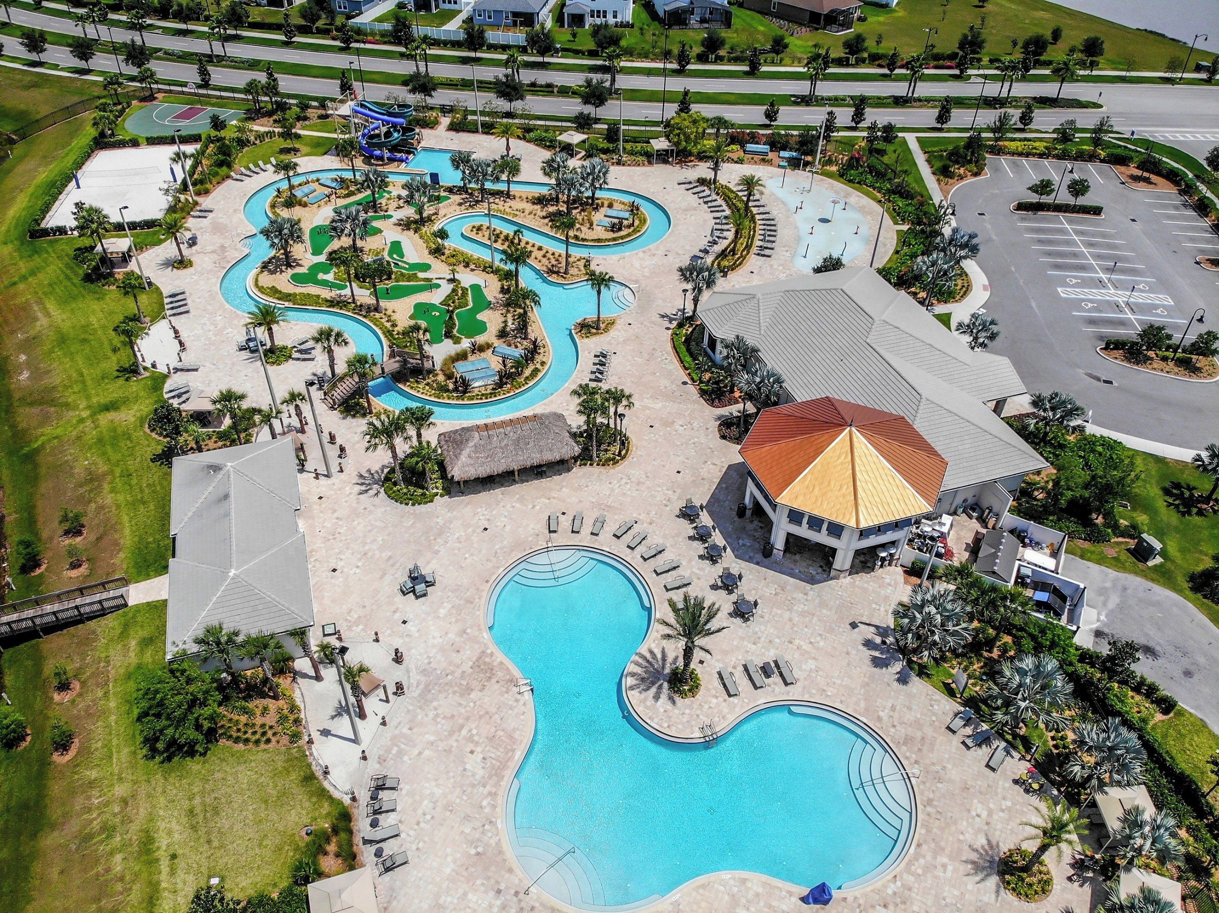 An aerial view of a resort with multiple swimming pools, a water park, and a large building with a red roof.