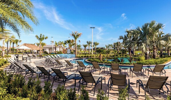 A resort pool area with multiple lounge chairs and a clear sky.
