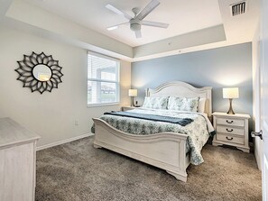 A bedroom with a bed, bedside tables, a ceiling fan, a window with blinds, and a wall-mounted mirror. - Lakeview Getaway near Theme Parks & Pools! (Kissimmee)