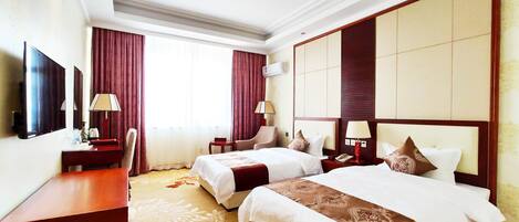 A hotel room with two beds, a TV, a desk, a chair, and a window with curtains.
