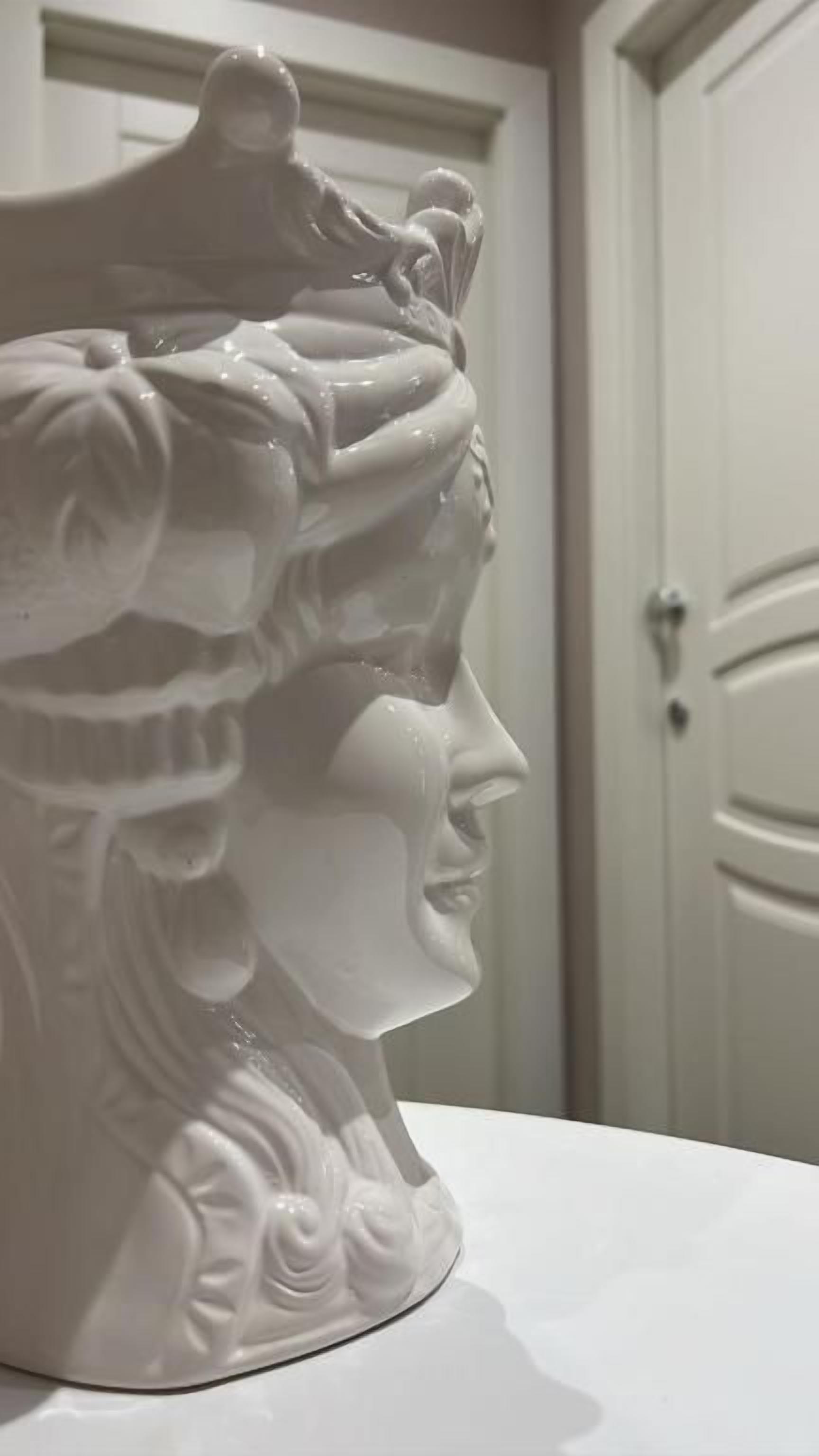 Un jarrón de cerámica blanca con un diseño detallado sobre una superficie blanca.