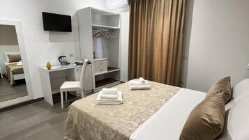 Habitación de hotel moderna con cama, escritorio, silla, armario y televisor.