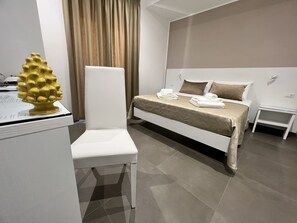 A hotel room with a bed, a chair, a nightstand, and a decorative golden object on a table. - Anfitrite B&B (Tropea)
