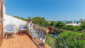 A balcony with two wicker chairs, a potted plant, and a metal railing overlooking a beach and parking area. - Apartment in Porto Recanati with 4 bedrooms sleeps 8 (Porto Recanati)