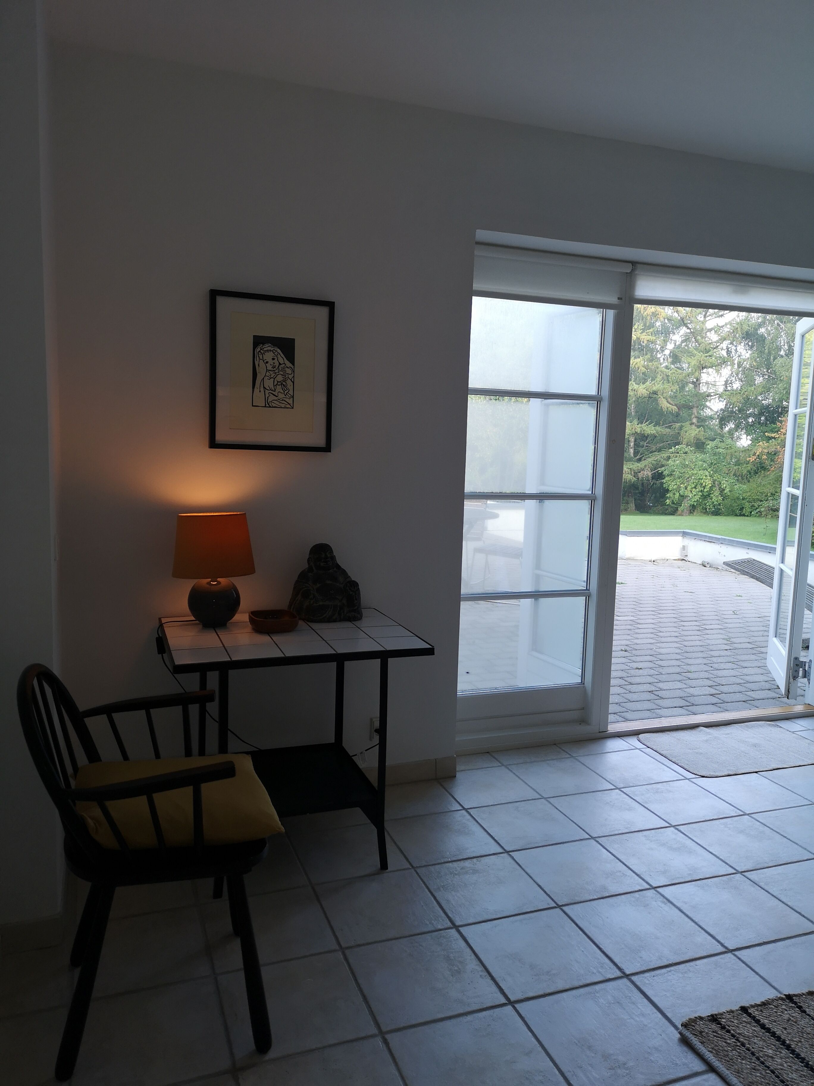 A room with a table, chair, lamp, and a framed picture on the wall.