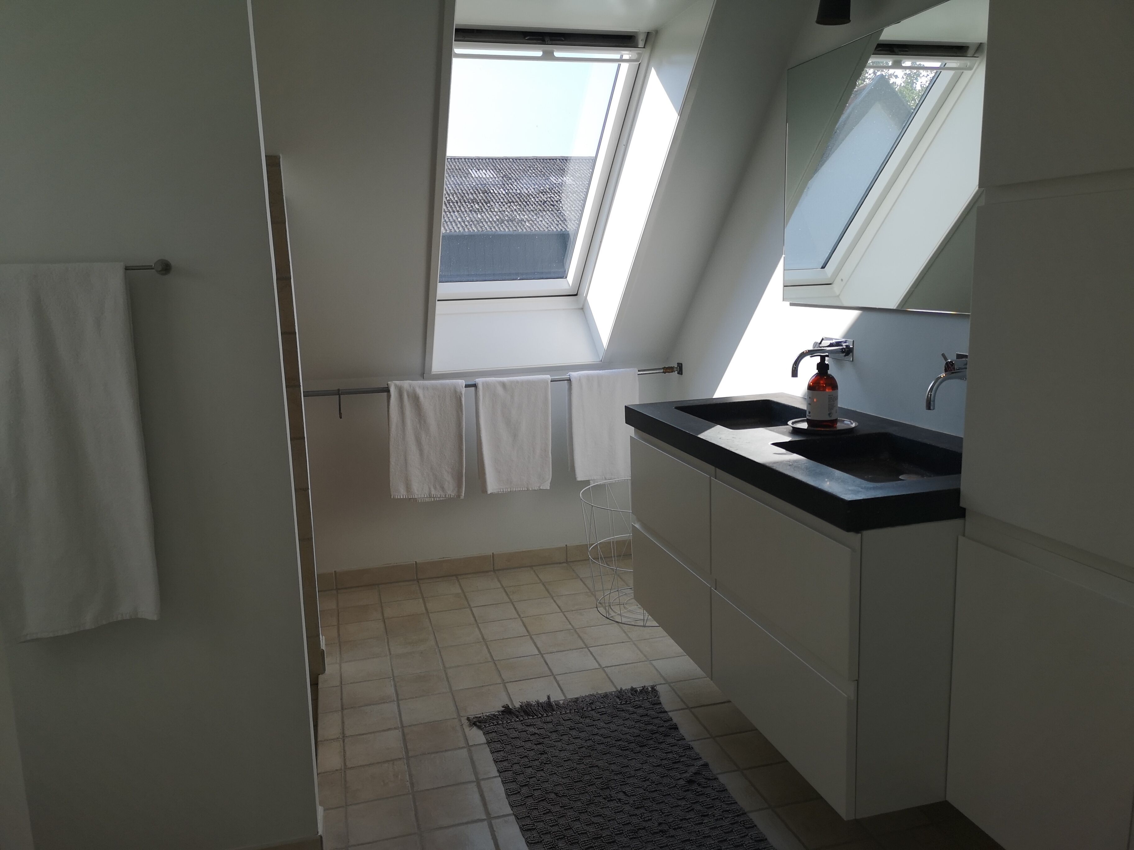 Une salle de bain moderne avec un puits de lumière, un lavabo et un porte-serviettes.