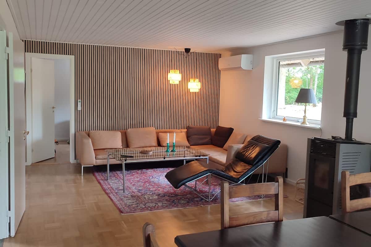 Ett modernt vardagsrum med en soffa, ett matbord och en öppen spis.