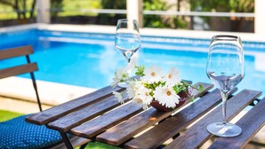 A wooden table with two wine glasses and a bowl of white flowers by a swimming pool. - CA SA Lloritana - 6 pax, private pool, wifi free! (Sencelles)