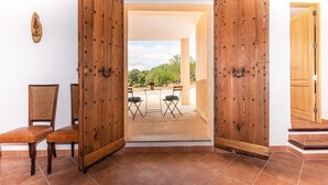 A room with two wooden doors leading to an outdoor patio with a table and chairs. - CA SA Lloritana - 6 pax, private pool, wifi free! (Sencelles)