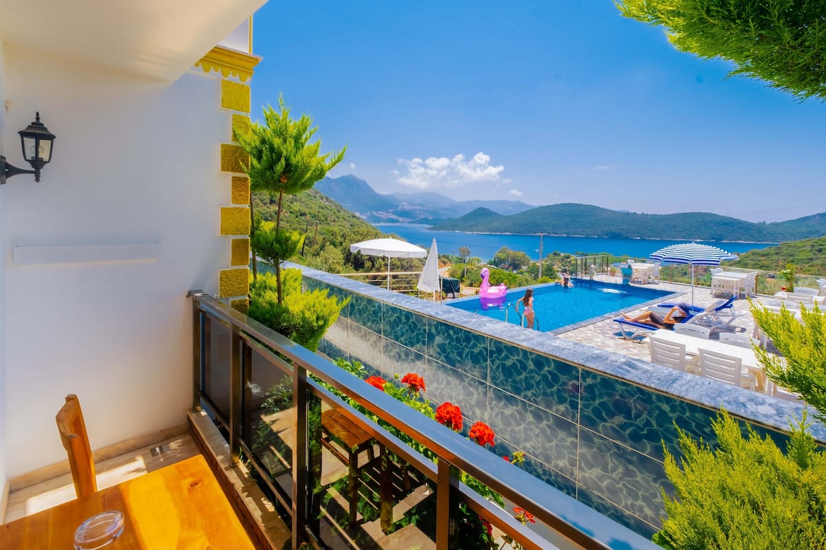 A balcony with a pool, overlooking a scenic landscape with mountains and a clear sky.