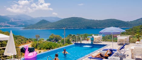 Una piscina al aire libre, sombrillas, sillones reclinables de piscina